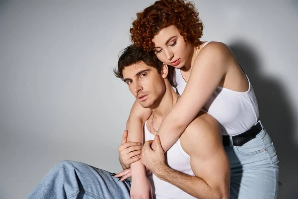 Pretty woman sitting on floor and hugging her appealing boyfriend who looking at camera, sexy couple — Stock Photo