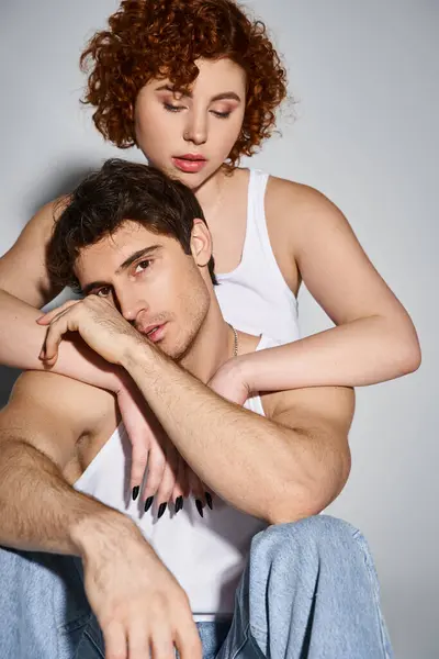 Pretty woman sitting on floor and hugging her handsome boyfriend who looking at camera, sexy couple — Stock Photo