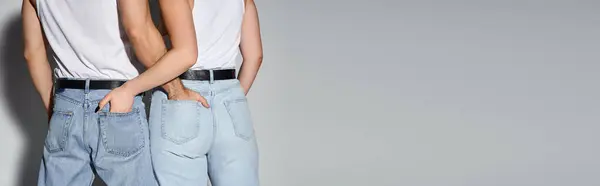 Vista posteriore di uomo e donna in jeans casual blu in posa con le mani in tasca, coppia sexy, banner — Foto stock