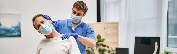 Guapo doctor con guantes ayudando a su paciente a estirar sus músculos, rehabilitación, estandarte - foto de stock