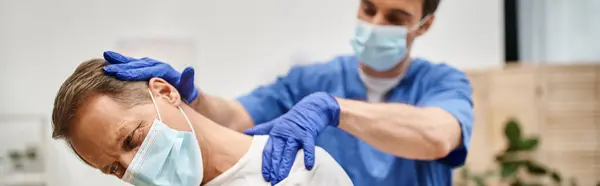 Guapo doctor con guantes ayudando a su paciente a estirar sus músculos, rehabilitación, estandarte - foto de stock