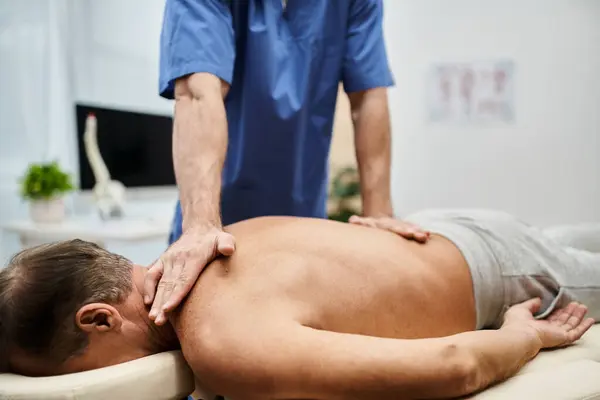 Cropped view of devoted doctor in medical robe massaging his mature patient during rehabilitation — Stock Photo