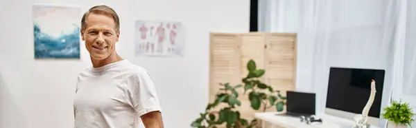 Handsome jolly mature patient in cozy attire posing in hospital ward and smiling at camera, banner — Stock Photo