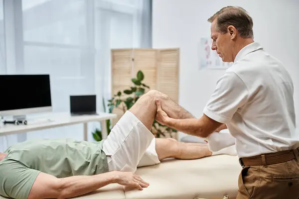 Bell'aspetto medico maturo controllare le ginocchia del suo paziente in ospedale, concetto di riabilitazione — Foto stock
