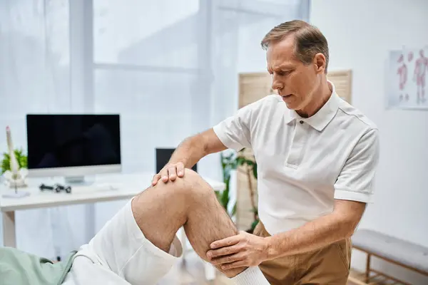Gut aussehender, reifer Arzt untersucht Knie seines Patienten im Krankenhaus, Rehabilitationskonzept — Stockfoto