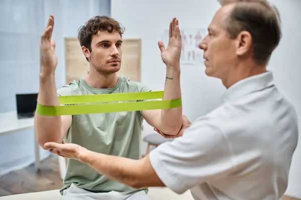 Good looking mature doctor checking up knees of his patient in hospital, rehabilitation concept — Stock Photo