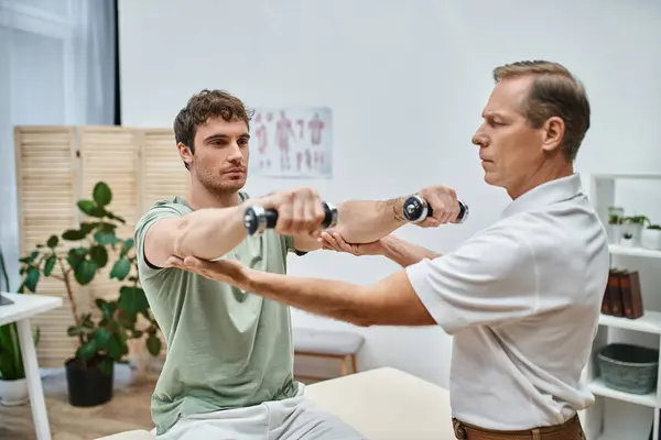 Good looking mature doctor checking up knees of his patient in hospital, rehabilitation concept — Stock Photo