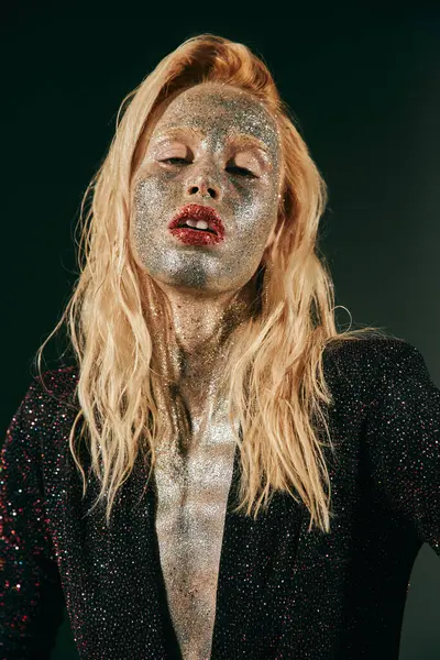 Portrait of blonde woman with glitter on face and body posing in shiny dress on black backdrop — Stock Photo
