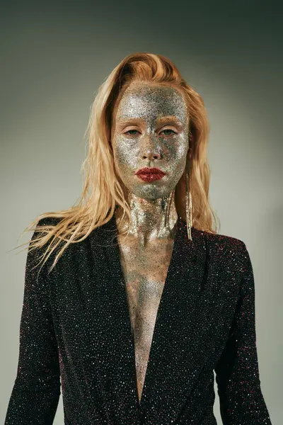Alluring blonde woman in shiny dress with glitter all over her body and face posing on grey backdrop — Stock Photo