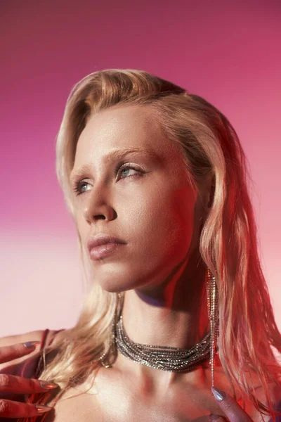 Portrait de femme séduisante et blonde en bijoux brillants et de luxe posant sur fond rose — Photo de stock