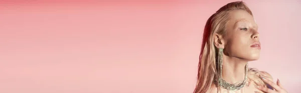 Schönheitsbanner der jungen blonden Frau in glänzender Halskette und Ohrringen posiert auf rosa Hintergrund — Stockfoto