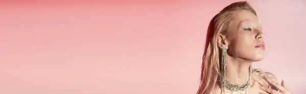 Beauty banner of young blonde woman in shiny necklace and earrings posing on pink background — Stock Photo