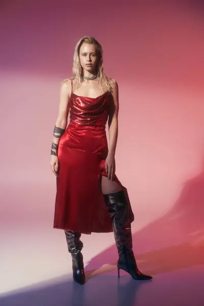 Good looking woman with accessories wearing stylish red dress looking at camera on pink backdrop — Stock Photo