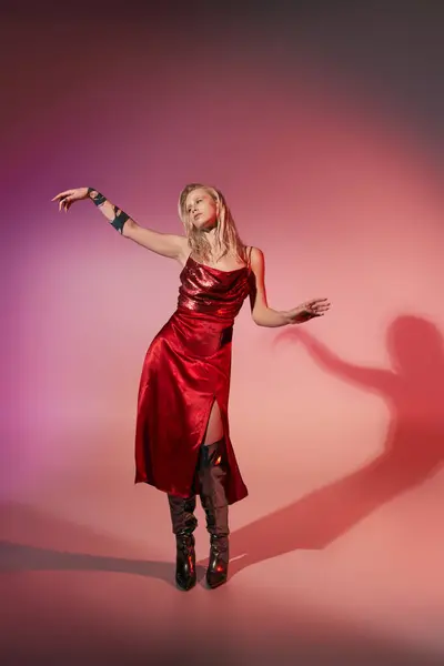 Appealing young woman with tattoo in red stylish dress posing in motion on pink background — Stock Photo