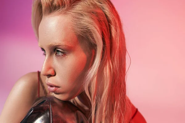 Modelo femenino joven de buen aspecto con ojos verdes en zapatos de cuero negro posando sobre fondo rosa — Stock Photo