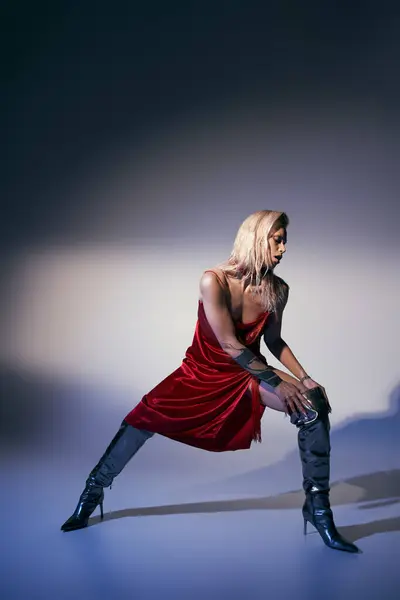 Modelo feminino elegante bonito em vestido vermelho e sapatos de couro posando em movimento no fundo cinza — Fotografia de Stock