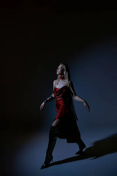 Belle femme en robe sexy rouge avec tatouage posant en mouvement sur fond sombre et regardant loin — Photo de stock