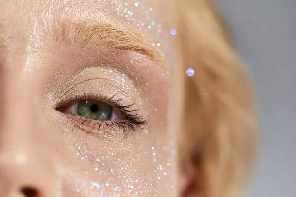 Close up of attractive woman with green eye and shiny highlighter on her face and looking at camera — Stock Photo