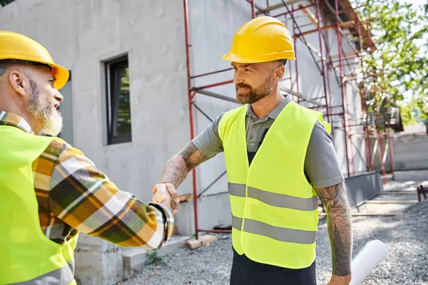 Travailleurs de la construction joyeux serrant la main et souriant les uns aux autres, constructeurs de chalets — Photo de stock