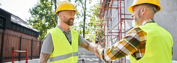 Jubelnde Bauarbeiter, die sich die Hände schütteln und anlächeln, Häuslebauer, Banner — Stockfoto