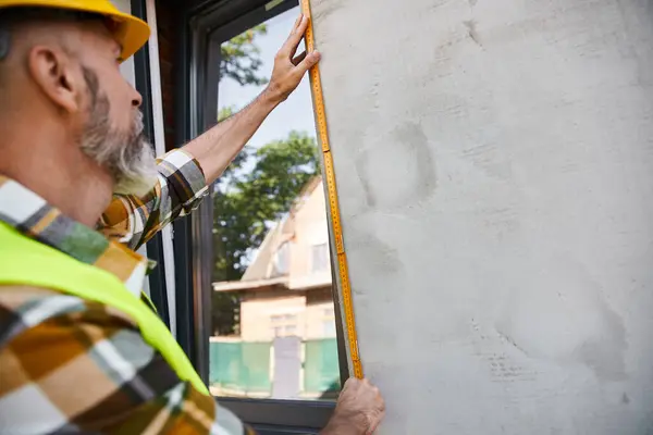 Добре виглядає працьовитий будівельник з бородатим мірним вікном зі стрічкою, будівельник котеджу — стокове фото