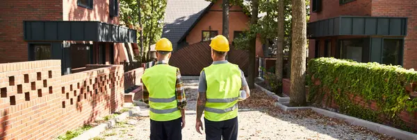 Back view of devoted construction workers in safety vests on site, cottage builders, banner — Stock Photo
