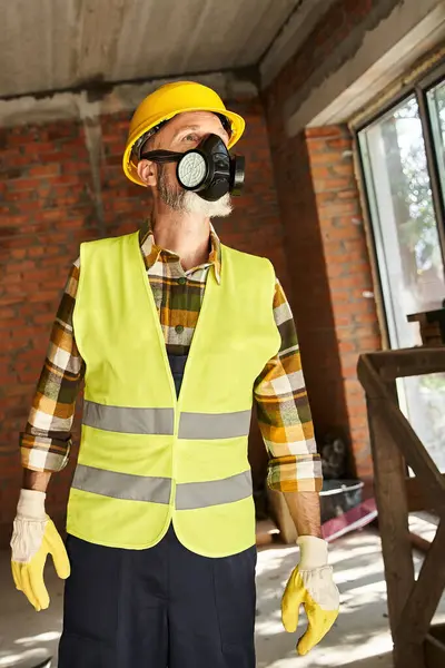 Vertical shot of cottage builder in safety helmet with dust mask working on construction site — Stock Photo