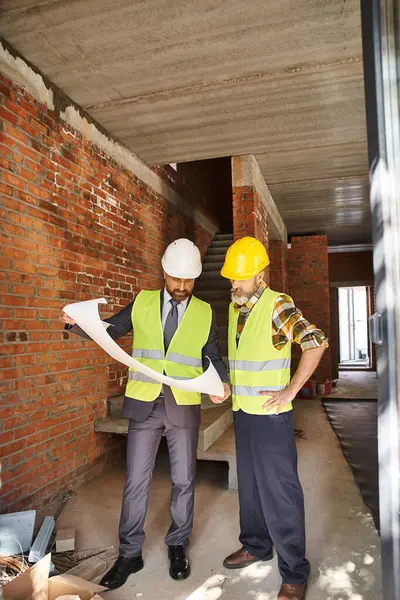 Handsome bearded cottage builder and architect working on construction site with blueprint — Stock Photo