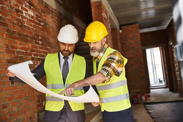 Devoted bearded cottage builder and architect working hard on construction site with blueprint — Stock Photo