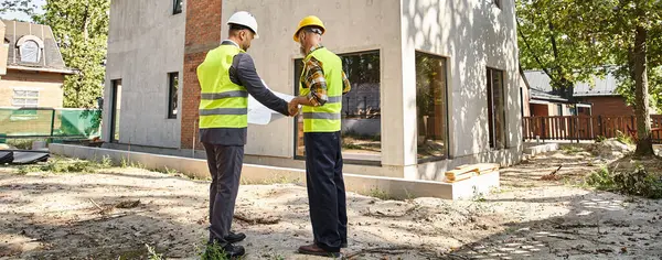 Constructeur de chalet dévoué et architecte tenant le plan et discuter du chantier de construction, bannière — Photo de stock