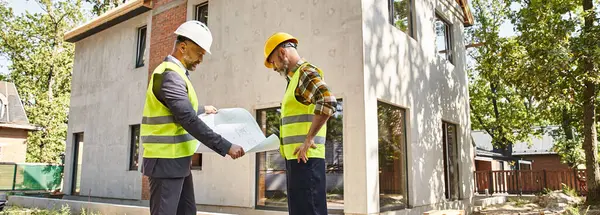 Devoted cottage builder and architect holding blueprint and discussing construction site, banner — Stock Photo