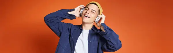 Banner of young man pleasure listening to music with headphones against terracotta background — Stock Photo