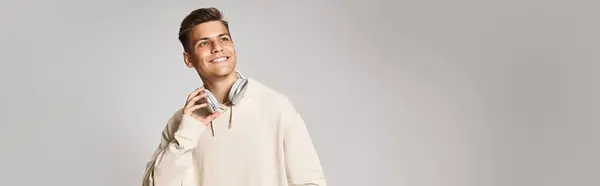 Banner of attractive young man in headphones with skateboard looking to up on light background — Stock Photo