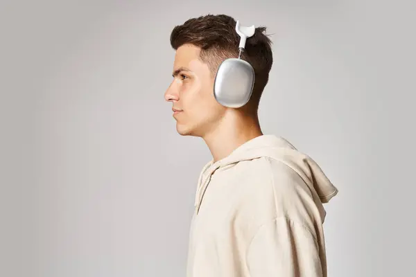 Selbstbewusster junger Mann mit braunen Haaren im Kopfhörer vor hellem Hintergrund — Stockfoto