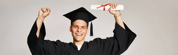 Banner eines lächelnden Studenten im Diplomkostüm, der froh ist, sein Studium auf grauem Hintergrund abgeschlossen zu haben — Stockfoto