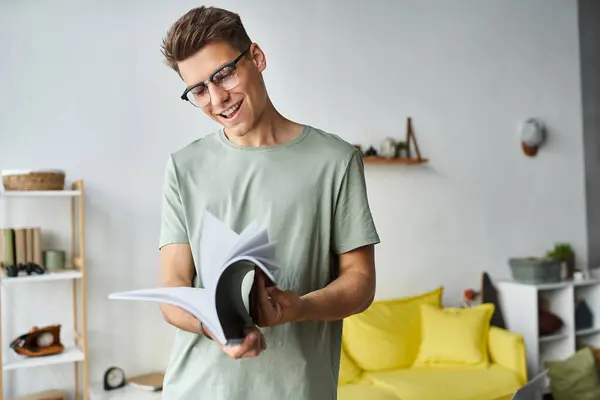 Happy and charming guy with brown hair and vision glasses in living room reading notes — Stock Photo