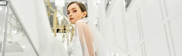 A young bride in a beautiful wedding dress stands gracefully in a hallway — Stock Photo
