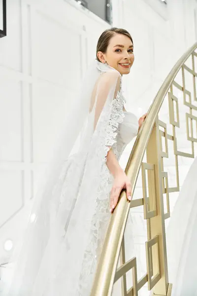 Молода брюнетка наречена у весільній сукні витончено стоїть на сходах у весільному салоні. — стокове фото