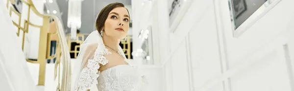 A young brunette bride in a wedding dress stands elegantly in a hallway, banner — Stock Photo
