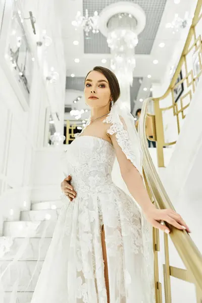 Junge brünette Braut im Brautkleid steht anmutig auf einer Treppe — Stockfoto