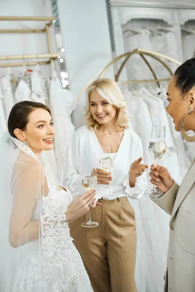 Três mulheres uma jovem noiva, sua mãe de meia-idade e uma dama de honra ficam lado a lado, cada uma segurando uma taça de champanhe.. — Fotografia de Stock