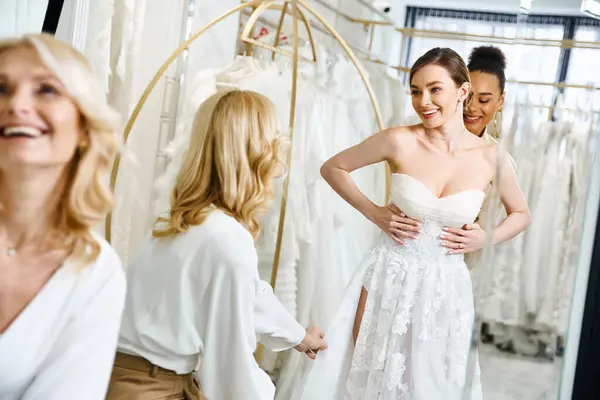 A young, beautiful bride in a white dress stands in front of a mirror, admiring her reflection in a wedding salon. — Stock Photo