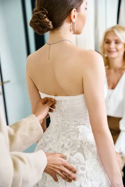A young, brunette bride in a white wedding dress prepares for her big day in a serene bridal salon. — Stock Photo