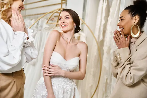Молодая брюнетка невеста в белом платье стоит рядом с двумя другими женщинами, источая элегантность и изящество. — стоковое фото