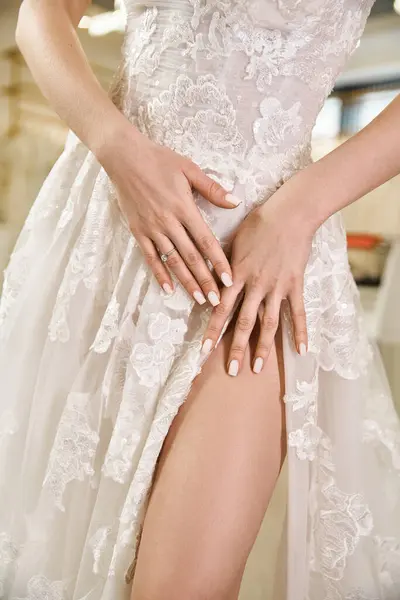 A young beautiful bride with brunette hair elegantly crosses her legs in a stunning white wedding dress. — Stock Photo