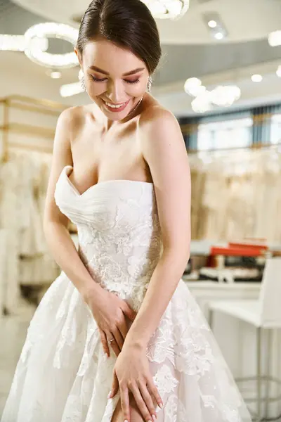 Uma jovem noiva morena está sorrindo feliz em um vestido branco dentro de um salão de casamento. — Fotografia de Stock