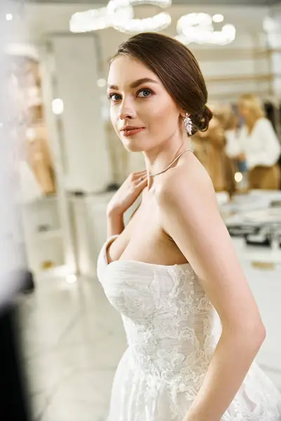 A young brunette bride in a white wedding dress strikes a pose for a picture in a wedding salon. — Stock Photo