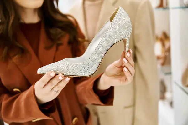 Une jeune belle mariée tient une paire de chaussures dans sa main tout en faisant du shopping pour son mariage — Photo de stock