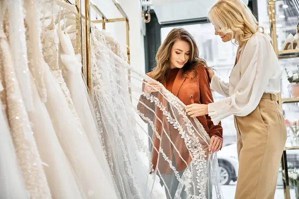 Due donne, una giovane sposa e sua madre, che ammirano gli abiti da sposa in un negozio di abiti da sposa con eccitazione e anticipazione. — Foto stock