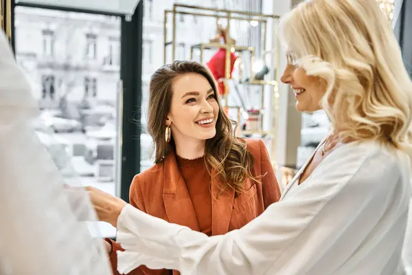 Two women in a store, a young beautiful bride and her mother, looking attentively at a mannequin dressed in a wedding gown. — Stock Photo